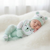 A 10-piece baby starter set including a white round neck shirt with embroidered bear face, full pajamas, a hooded sheet, bib, cap, face towels, and booties. The set has a bear-themed design.