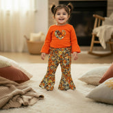 Child wearing an orange sweater with a floral heart design and colorful pants