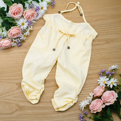 Yellow baby romper with a bow on a wooden surface