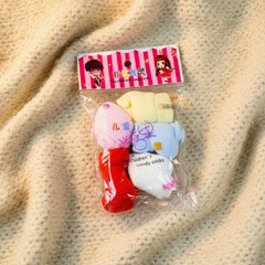 Packaged children's toys with a pink and white striped label on a wooden surface
