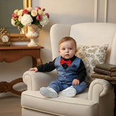 Children's formal outfit with black shirt, red bow tie, blue pants, vest, white shoes, and sunglasses on a wooden surface.