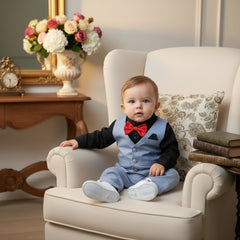 Children's formal outfit with black shirt, red bow tie, blue pants, vest, white shoes, and sunglasses on a wooden surface.