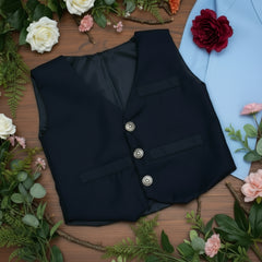 Navy blue vest with silver buttons on a wooden surface