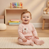 Pink baby onesie with a bow on a wooden surface