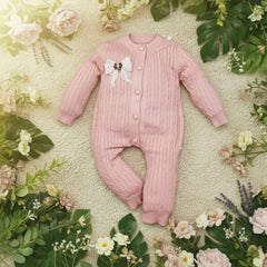 Pink baby onesie with buttons on a wooden surface