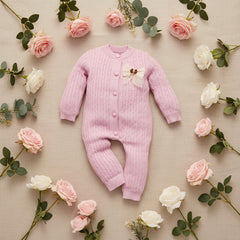 Purple baby outfit with a floral bow on a wooden surface