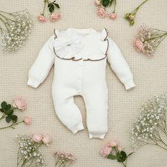 White baby romper with a decorative collar on a wooden surface