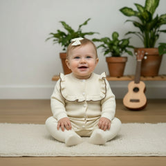 White baby romper with a bow on a wooden surface