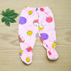 Pink baby pants with colorful fruit pattern on a wooden surface