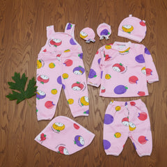 Children's pink outfit set with fruit patterns on a wooden surface