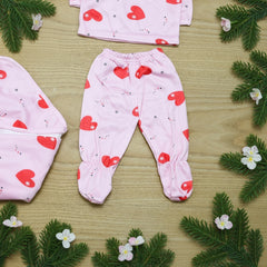 Baby outfit with pink pants and red heart patterns on a wooden surface