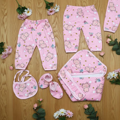Pink baby outfit set with bear patterns on a wooden surface