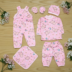 Pink baby outfit set with bear patterns on a wooden surface