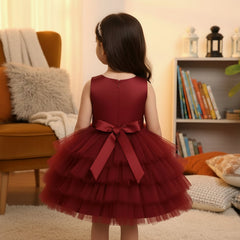 Young girl in a red dress standing in a cozy living room.