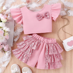 A baby toddler girl's dress with ruffle sleeves and sequin embellishments on the shorts, presented on a soft background alongside accessories.