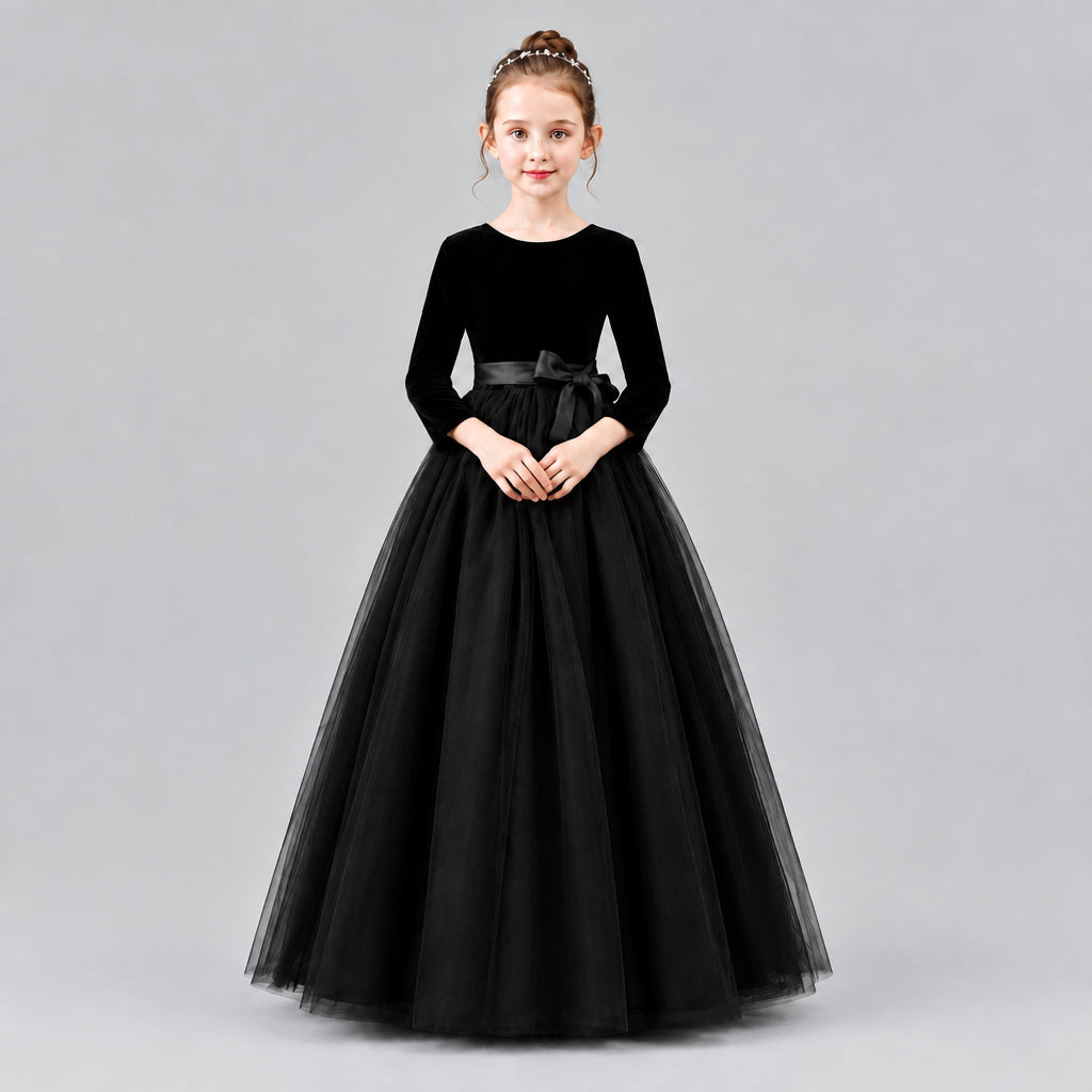 A young girl modeling a formal ball gown with a velvet long-sleeve bodice, a satin waistband, and a voluminous tulle skirt.