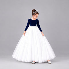 A young girl modeling a formal ball gown with a velvet long-sleeve bodice and a voluminous net skirt.