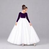 A young girl modeling a formal ball gown with a velvet long-sleeve bodice and a voluminous net skirt.
