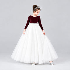 A young girl modeling a formal ball gown with a velvet long-sleeve bodice and a voluminous satin skirt.