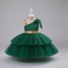 A green one-shoulder toddler party dress with a tiered tulle skirt, a gold sequined waistband, and a matching bow on the shoulder.