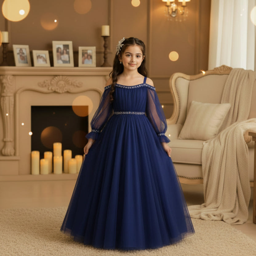 A young girl wearing a blue off-the-shoulder tulle ball gown with silver beaded trim at the neckline and waist.