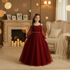 A young girl wearing a formal off-the-shoulder ball gown in deep burgundy red tulle with silver rhinestone trim.