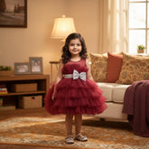 A sleeveless, knee-length red mesh frock with a white bow at the front displayed on a mannequin.