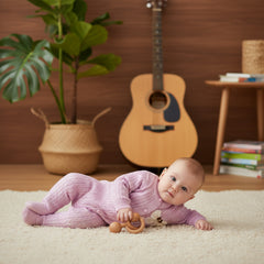 Purple baby outfit with a floral bow on a wooden surface