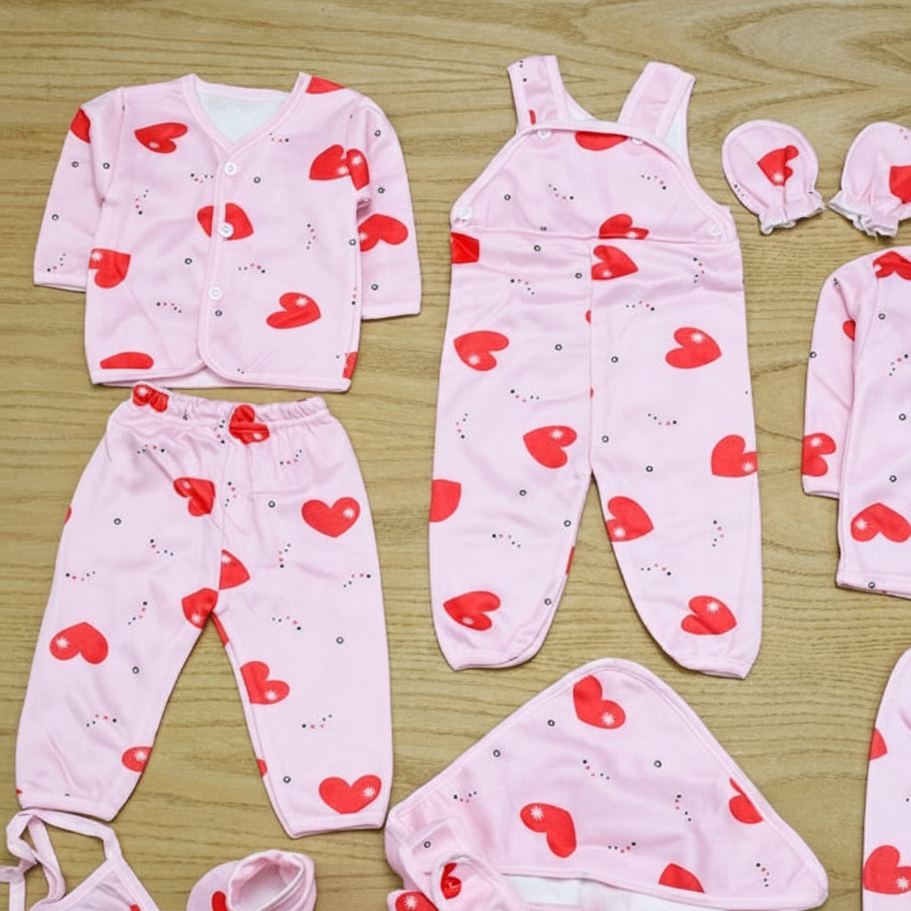 Baby clothing set with pink hearts on a wooden surface