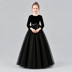 A young girl modeling a formal ball gown with a velvet long-sleeve bodice, a satin waistband, and a voluminous tulle skirt.