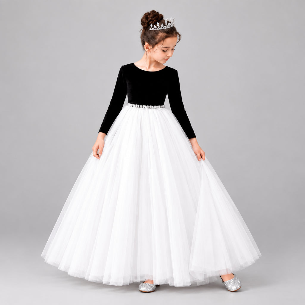 A young girl modeling a formal ball gown with a velvet long-sleeve bodice and a voluminous net skirt.