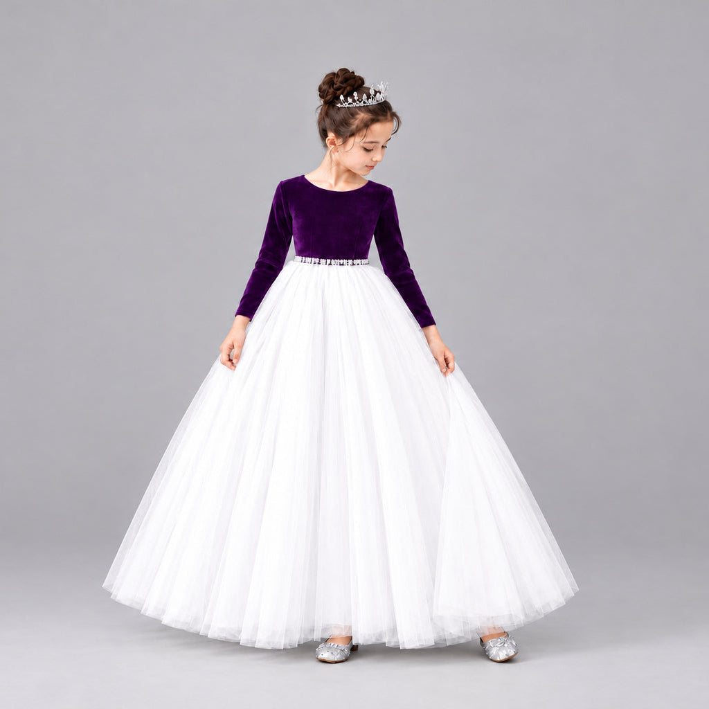 A young girl modeling a formal ball gown with a velvet long-sleeve bodice and a voluminous net skirt.