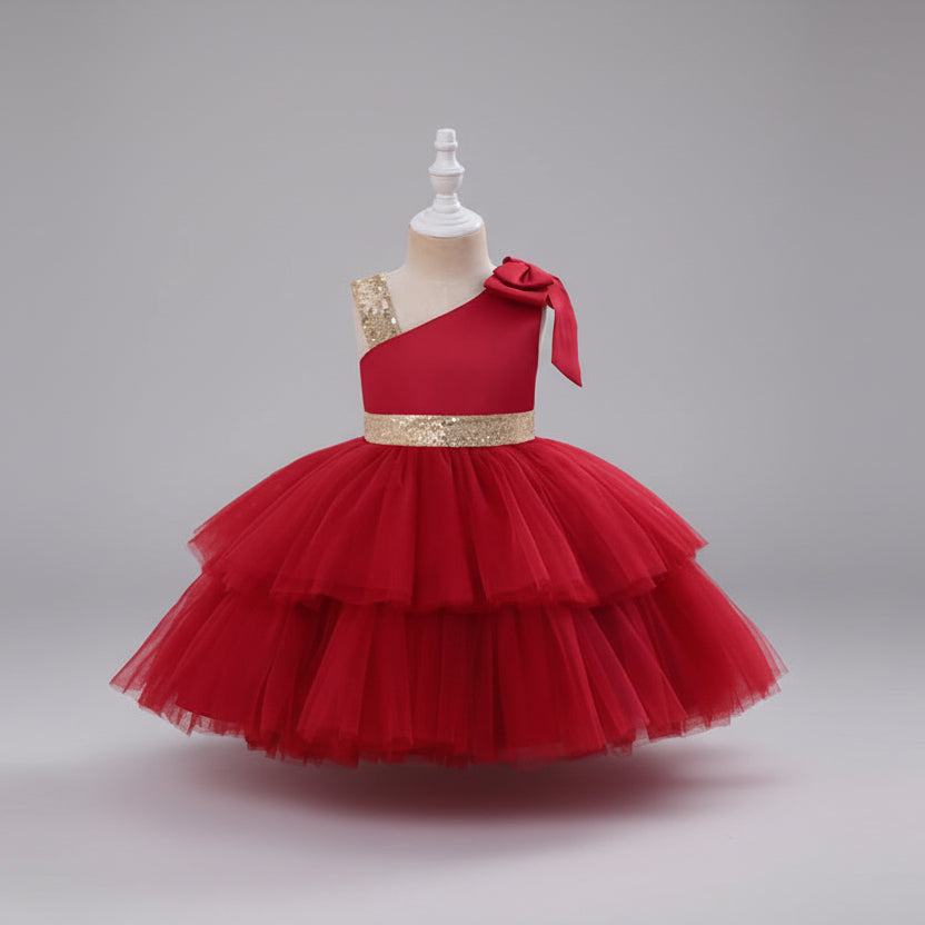 A red one-shoulder party dress with a tiered tulle skirt and a gold sequined waistband, displayed on a mannequin.
