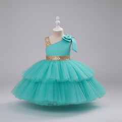 An aqua one-shoulder toddler party dress with a tiered tulle skirt, a gold sequined waistband, and a matching red bow on the shoulder.