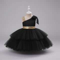 A black one-shoulder toddler party dress with a tiered tulle skirt, a gold sequined waistband, and a matching bow on the shoulder.