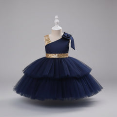 A navy blue one-shoulder toddler party dress with a tiered tulle skirt, a gold sequined waistband, and a matching bow on the shoulder.